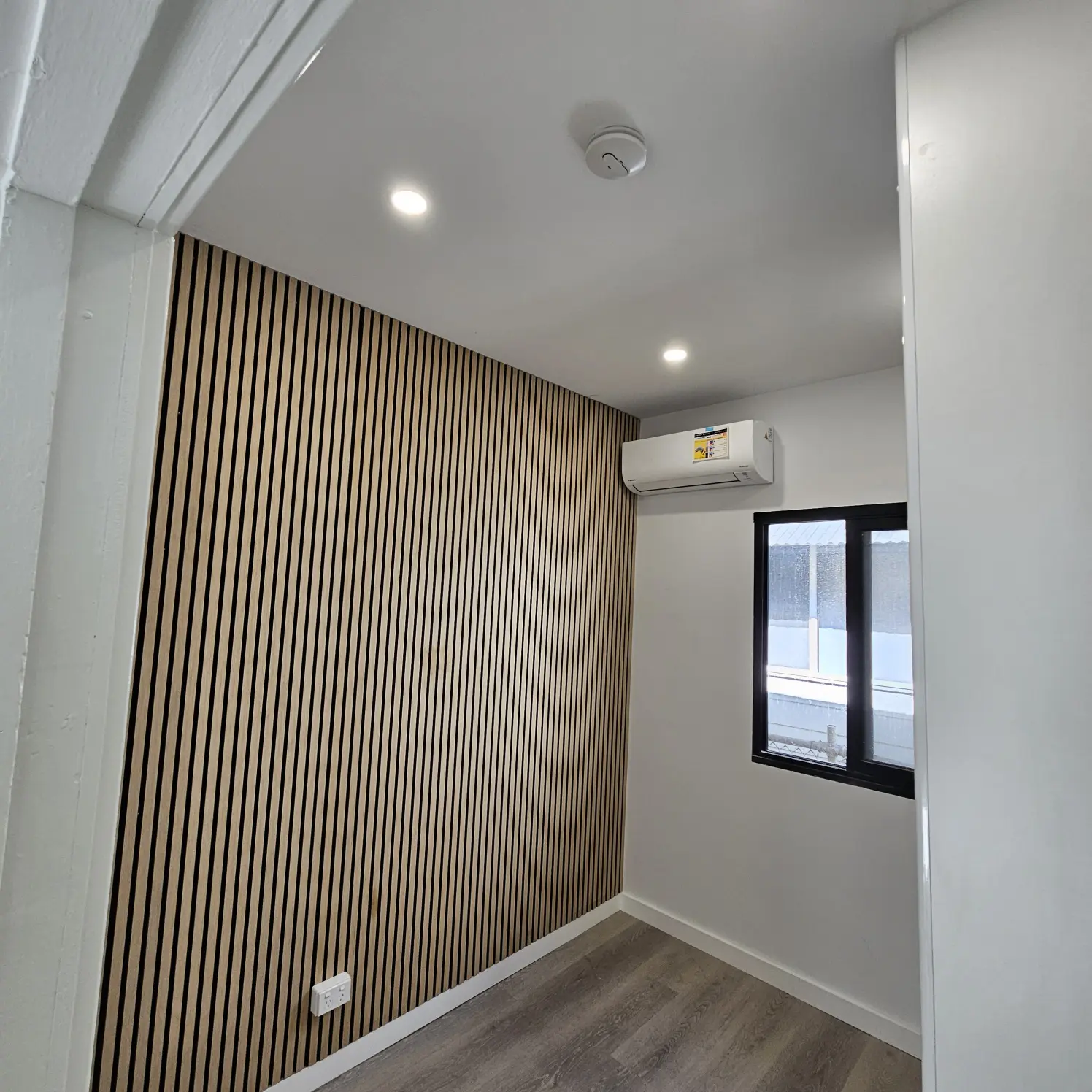 Bedroom with vertical timber slat feature wall, split-system air conditioner and LED downlights